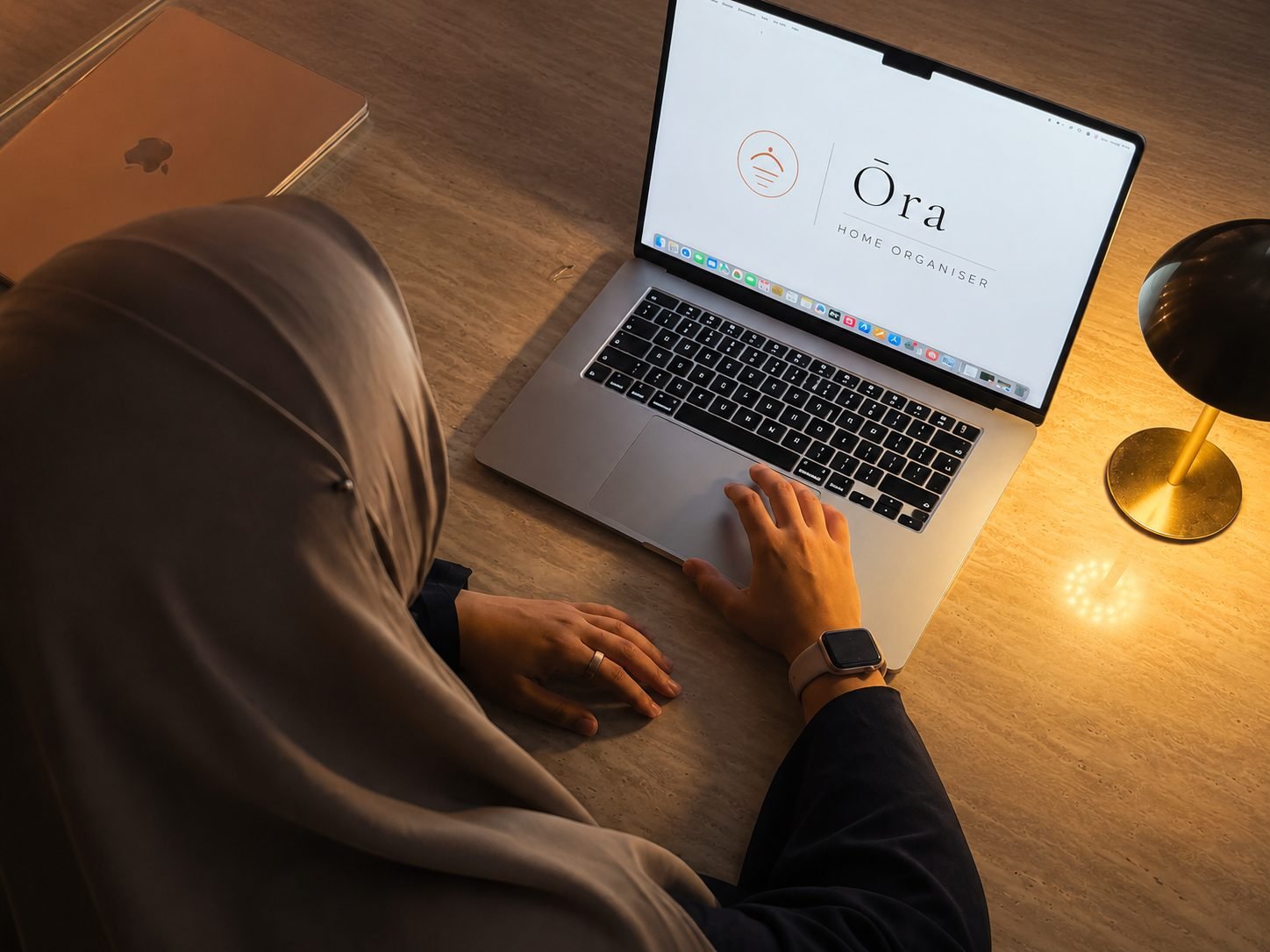 Sana, fondatrice d'Ōra, de dos devant son ordinateur portable affichant le logo Ōra